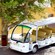 A shuttle bus near a tree, a bin and a museum with 2 rusty cannons near the entrance